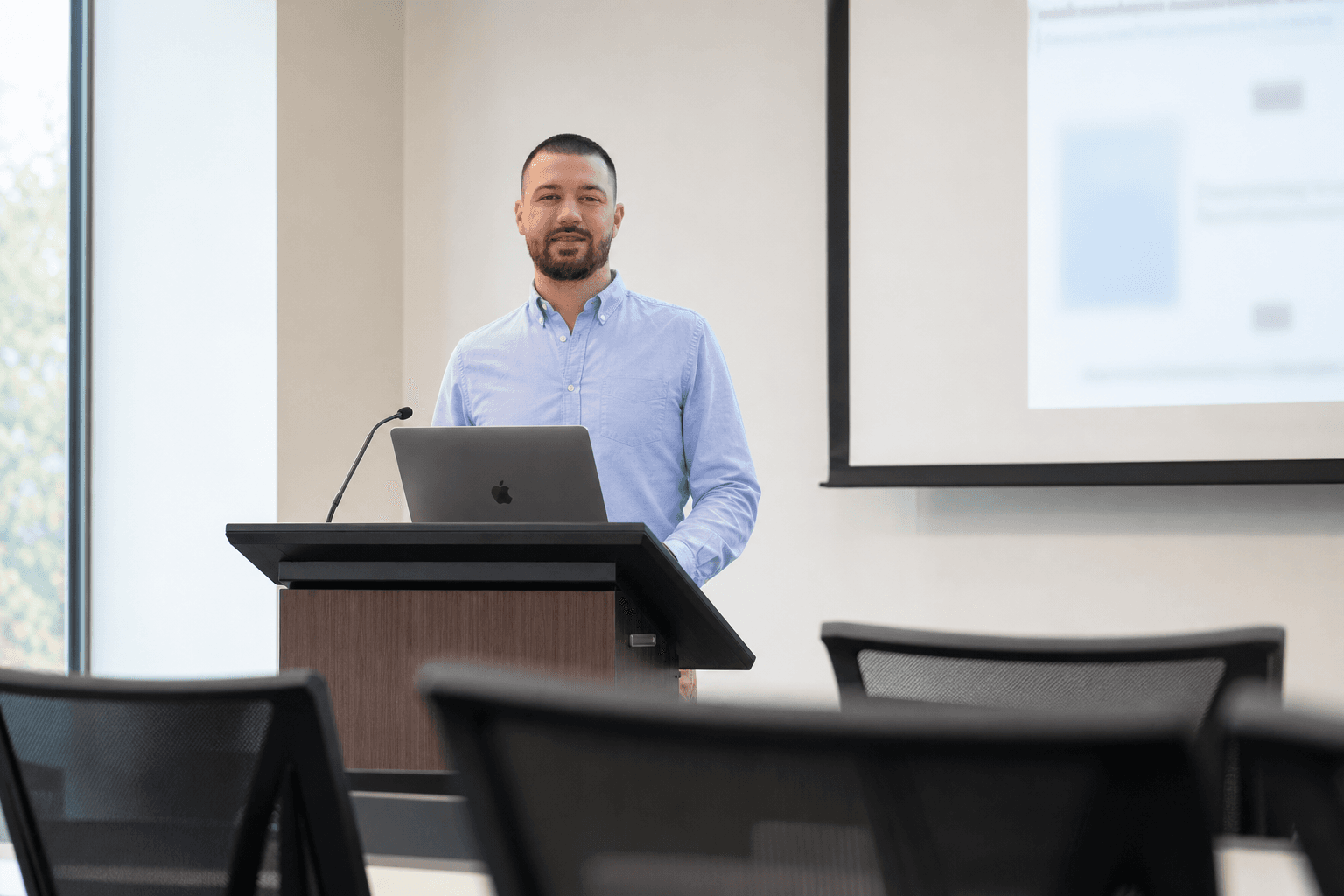 Chandler Talley — teaching at a classroom lectern with a laptop